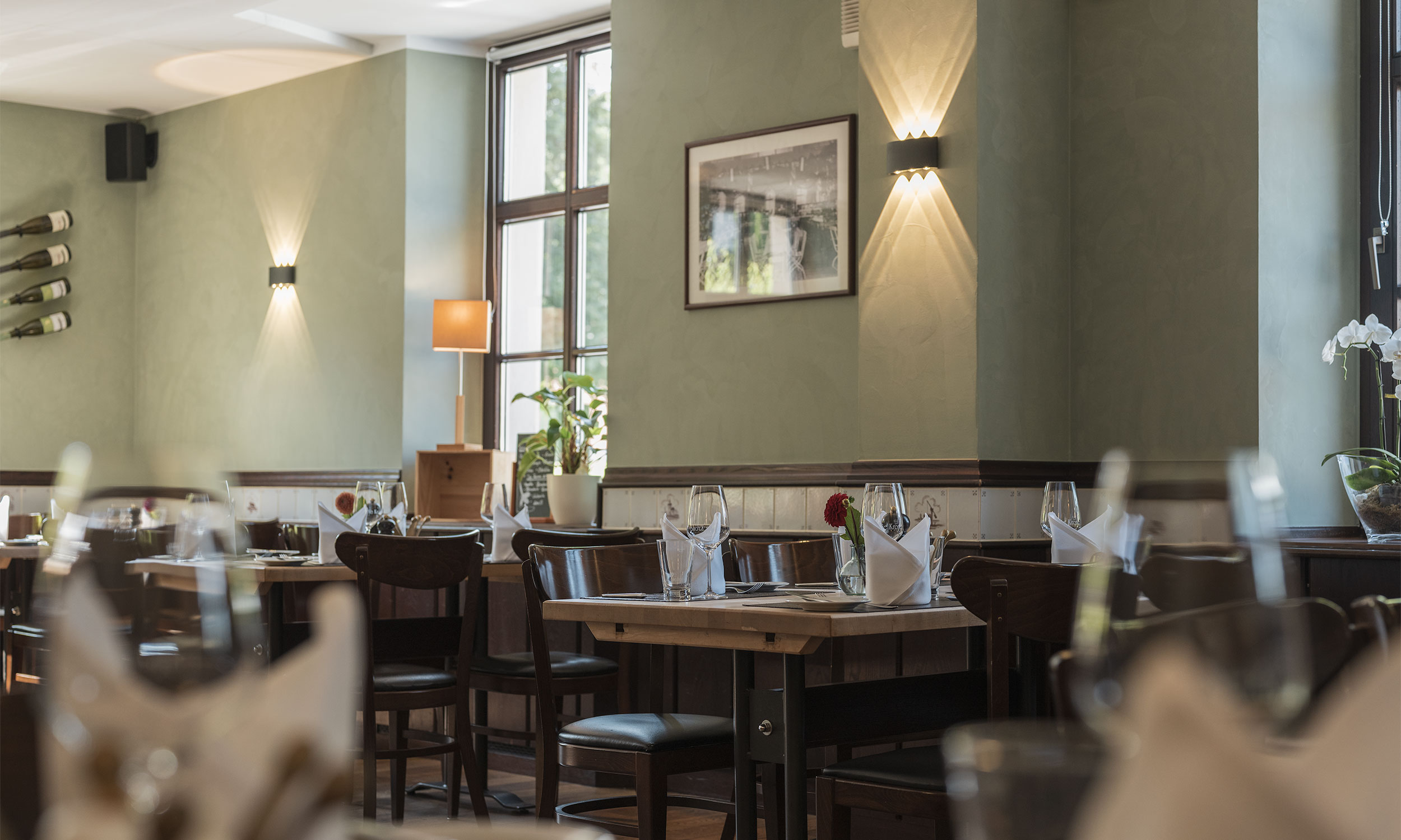 Blick in den schön gestalteten Speiseraum des Restaurants Die Krone Homberg in Ratingen. Die Tische sind mit Gläsern, Besteck und Servietten eingedeckt